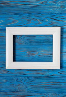 Ahşap mavi masa üzerinde beyaz fotoğraf çerçevelemek. Vintage.