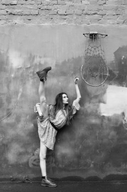 Balerin kısa elbise ve çizmeler beton duvara yakın