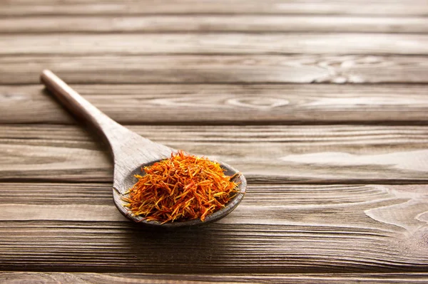 Spice saffron in wooden spoon on wooden table. — Stock Photo, Image