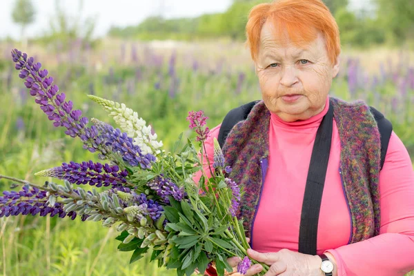 Femme âgée avec un bouquet de fleurs sauvages dans le champ. Été . — Photo