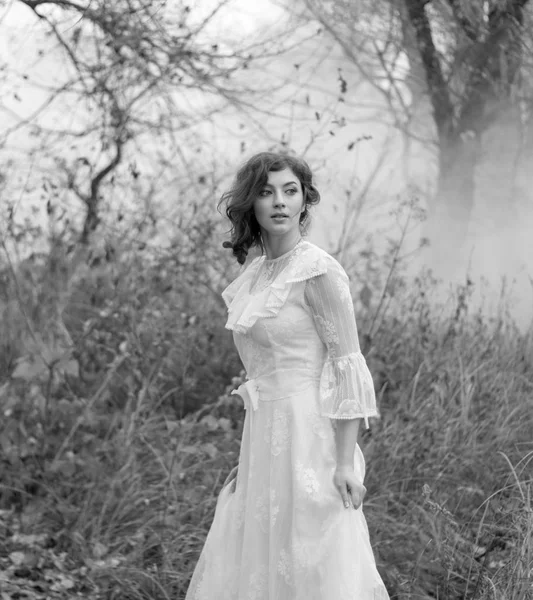 lady in gorgeous vintage white dress in the forest. Black and w