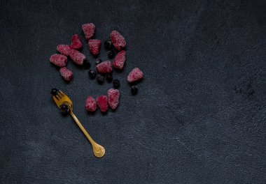 Donmuş ahududu, kara frenk üzümü ve siyah taş arka planda altın çatal. Sağlıklı yemek fikri. Üst görünüm.