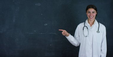 Güzel kadın doktor (öğrenci) portre siyah bir arka plan üzerinde siyah bir yönetim kurulu tarafından duruyor. Konsept: fikirler, okul, üniversite, kimya, bilim, öğretmenler, bellek, biyoloji, hekim, üniversite.