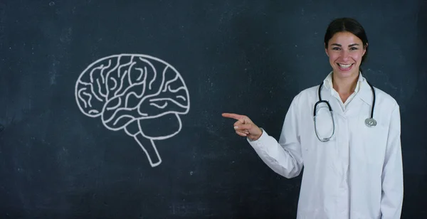 Portrét krásné ženské lékaře (student) ukazující na mozek, mysl, poblíž černé desce. Koncepce: myšlenky, škola, univerzita, chemie, věda, učitelů, paměť, biologie, lékař, škola — Stock fotografie