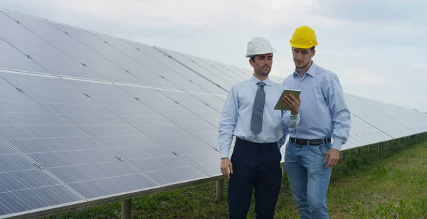 Dos socios técnicos expertos en paneles fotovoltaicos solares, el control remoto realiza operaciones rutinarias para monitorear el sistema utilizando energía limpia y renovable. El concepto de tecnología de soporte remoto . —  Fotos de Stock