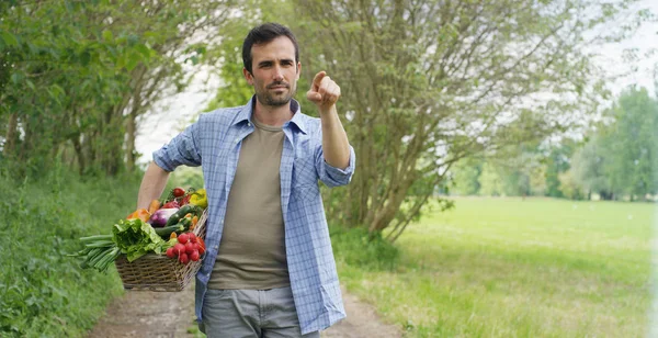 Portrait d'un jeune agriculteur heureux tenant des légumes frais dans un panier. Sur un fond de nature Le concept de produits biologiques, bio, bio écologie, cultivé par ses propres mains, végétariens, salades saines — Photo