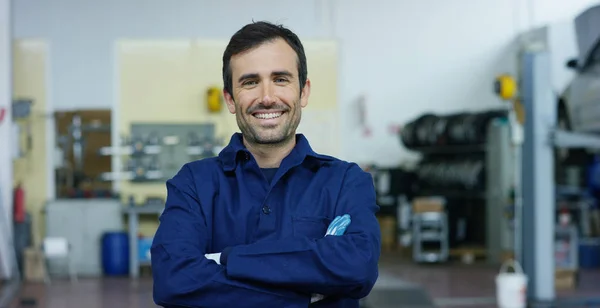 Portret van een jonge mooie automonteur in een autowerkplaats, op de achtergrond van service. Concept: reparatie van machines, foutendiagnose, reparatiespecialist, technisch onderhoud en boordcomputer — Stockfoto