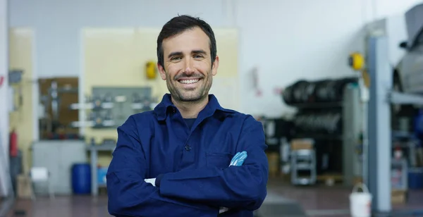 Retrato de um jovem mecânico de carro bonito em uma oficina de carro, no fundo do serviço. Conceito: reparação de máquinas, diagnóstico de falhas, especialista em reparação, manutenção técnica e computador de bordo — Fotografia de Stock