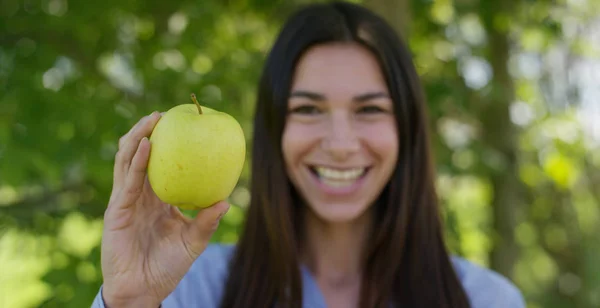 Gadis muda cantik memegang apel hijau matang segar di tangan, di latar belakang alam. Konsep: biologi, produk bio, ekologi biologi, buah yang tumbuh, diet, produk alami yang bersih dan segar . — Stok Foto