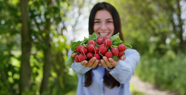 Vacker ung flicka som håller en ren Rädisa i handen, i bakgrunden av naturen. Koncept: biologi, bioprodukter, bio ekologi, odla grönsaker, ren och fräsch naturprodukt, vegetarianer, friska — Stockfoto