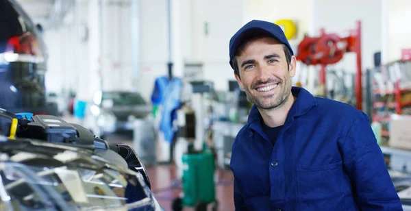 Retrato de um carro bonito jovem mecânico em uma oficina de carro, no fundo de um serviço de carro Conceito de reparação de máquinas, diagnóstico de falhas, especialista em reparação, manutenção técnica a bordo do computador — Fotografia de Stock