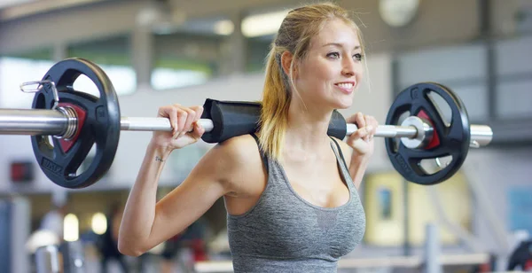 Jeune belle fille dans la salle de gym faire des exercices sur le squat avec un haltère, l'amélioration des muscles des fesses et des jambes Concept amour sports assister à une salle de gym bonne nutrition corps mince pour être en bonne santé — Photo