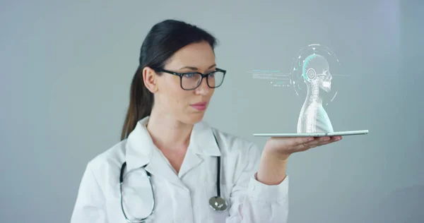 La doctora con bata blanca y estetoscopio, con tableta holográfica representaba el cuerpo del paciente, los pulmones del corazón, los músculos, los huesos. Concepto: Medicina futurista, asistencia mundial y el futuro . —  Fotos de Stock