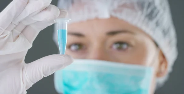 En un laboratorio, un científico con una pipeta analiza un líquido de color para extraer el ADN y las moléculas en los tubos de ensayo. Concepto: investigación, bioquímica, naturaleza, medicina farmacéutica —  Fotos de Stock