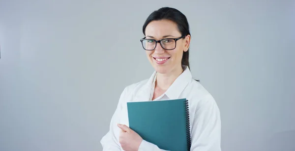 Retrato de una doctora con bata blanca y estetoscopio sonriendo mirando a la cámara sobre fondo blanco. Concepto: médico, cuidado de la salud, amor por la medicina . — Foto de Stock
