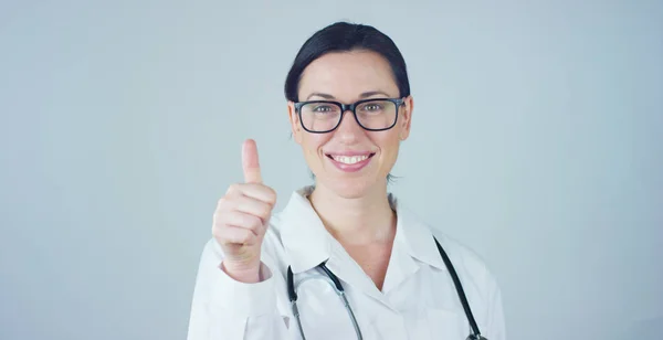 Porträtt av en kvinnlig läkare med vit päls och stetoskop leende tittar in kameran på vit bakgrund. Koncept: läkare, sjukvård, kärlek till medicin. — Stockfoto
