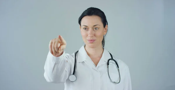 Портрет жінки-лікаря з білим пальто і стетоскопом, який посміхається, дивлячись в камеру на білому тлі. Концепція: лікар, охорона здоров'я, любов до медицини . — стокове фото