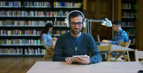 若い男性と女性は図書館で勉強、読書、または全体の静けさとリラクゼーションで、コンピューターで音楽を聴くのグループ。文化、教育、緩和および研究の概念 — ストック動画