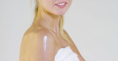 Gülümseyen ve makyaj, krem, beyaz bir arka plan üzerinde karalama omuz olmadan kamera bakıyor güzel bir genç kız portresi. Kavram: doğal güzellik, gençlik, Cilt Bakımı, her zaman genç, kendini sev.