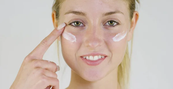 Retrato de uma linda menina sorrindo e olhando para a câmera, sem maquiagem, rosto manchado de creme, em um fundo branco.Conceito: beleza natural, juventude, cuidados com a pele, sempre jovem, ame a si mesmo. . — Fotografia de Stock