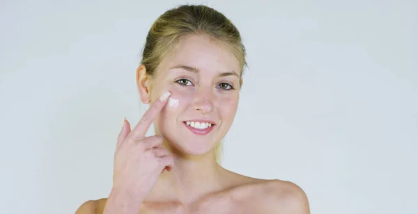 Retrato de uma linda menina sorrindo e olhando para a câmera, sem maquiagem, rosto manchado de creme, em um fundo branco.Conceito: beleza natural, juventude, cuidados com a pele, sempre jovem, ame a si mesmo. . — Fotografia de Stock