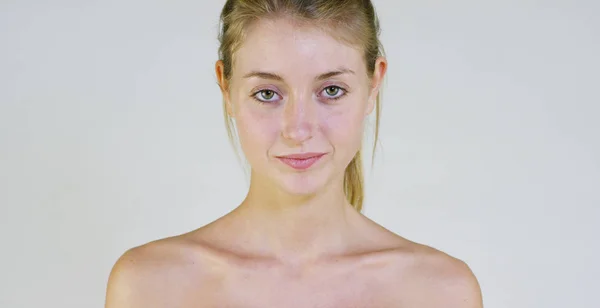 Portrait of a beautiful young girl smiling and looking at the camera, without makeup, after cream, on a white background. Concept: natural beauty, youth, skin care, always young, to love yourself. — Stock Photo, Image