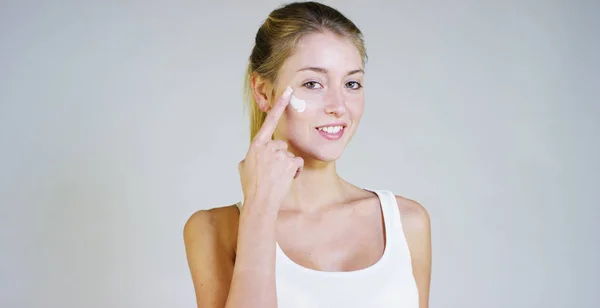 Portrait d'une belle jeune fille souriante et regardant l'appareil photo, sans maquillage, visage craquant de crème, sur un fond blanc.Concept : beauté naturelle, jeunesse, soins de la peau, toujours jeune, aimez-vous . — Photo