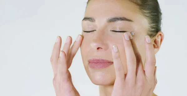 Ritratto di una bella ragazza che sorride e guarda la macchina fotografica, senza trucco, imbrattando il viso di crema, su sfondo bianco.Concetto: bellezza naturale, giovinezza, cura della pelle, sempre giovane, ama te stesso . — Foto Stock