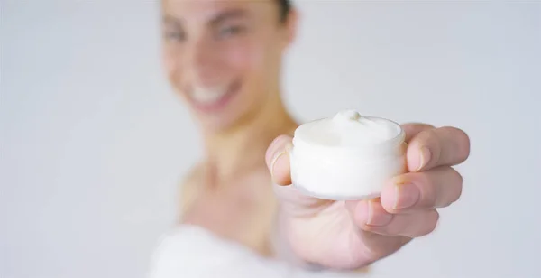 Retrato de uma bela jovem, em close-up mostra creme e sorrindo, no fundo branco. Conceito: vitaminas, fresco, fitness, produtos biológicos, procedimentos de spa, cuidados com a pele, amar a si mesmo, creme cãibras . — Fotografia de Stock