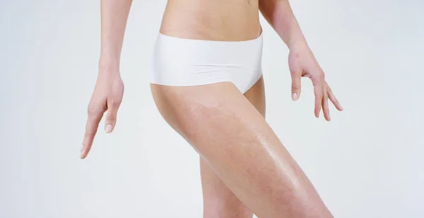 Young girl smears cream her beautiful, perfect body(waist), on a white background. Concept: vegetarian, diet, proper nutrition, spa procedures, fresh, fitness, bio products, body care, perfect skin. — Stock Photo, Image