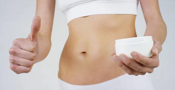 Giovane ragazza spalma crema il suo bel corpo perfetto (vita), su uno sfondo bianco. Concetto: vegetariano, dieta, corretta alimentazione, procedure termali, fresco, fitness, prodotti biologici, cura del corpo, pelle perfetta . — Foto Stock