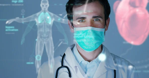 Un médico, cirujano, examina una placa holográfica digital tecnológica representada el cuerpo del paciente, los pulmones del corazón, los músculos, los huesos. Concepto: Medicina futurista, asistencia mundial y el futuro — Foto de Stock