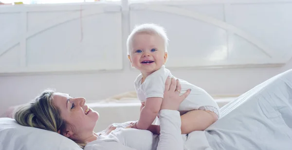 Os melhores momentos da vida, uma jovem mãe amorosa e feliz abraça um filho de enfermagem, em um cobertor branco de neve, em um fundo branco. conceito de amor, família e felicidade — Fotografia de Stock