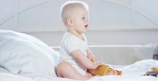 赤ちゃんは、大きな青い目と明るい色の髪を持つ少年に座っている雪白い毛布に笑顔、白い背景の上の彼女の母を見て. — ストック写真