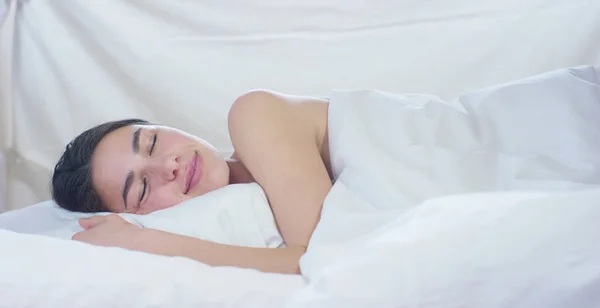 Un simple día de trabajo para una hermosa joven que duerme en una cama cálida, cubierta con una suave manta blanca cálida, sobre un fondo blanco . —  Fotos de Stock