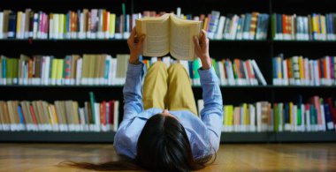 Mutlu ve kaygısız bir kitaplıkta kitap okuma eğitimi güzel bir genç kadın. Konsept: eğitim, portre, Kütüphane ve çalışkan, sakin ol.