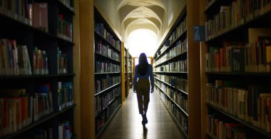 Portrait of a beautiful young woman smiling happy in a library holding books after doing a search and after studying. Concept: educational, portrait, library, and studious. clipart