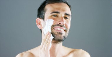 A beautiful portrait of man before to shave using shaving foam for better perfect shave and protect your skin from irritation. Concept: barber, shaving cream and man. clipart