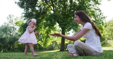 güneşli bir yaz günü A yeni doğan gülümseyen anne mutlu ve spensierian doğru çalışan ilk adımı alır. Hayatında hiç unutmayacak ilk adımlar. Ve annem ona ilk adımlar atmaya yardımcı olur.