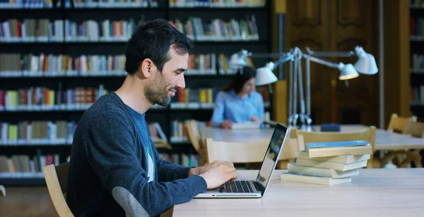 A group of young men and women studying in the library, reading books, or listening to music on the computer in total silence and relaxation. Concept of culture, education, relaxation and study