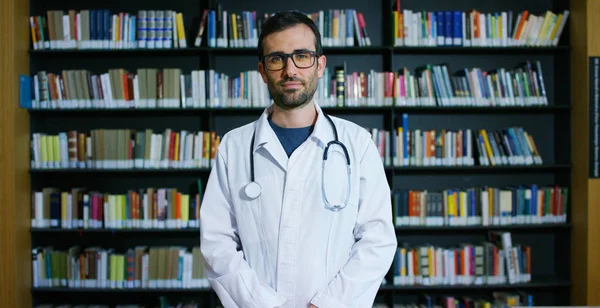 Jeune Bel Homme Médecin Dans Une Bibliothèque Souriant Heureux Tenant — Photo