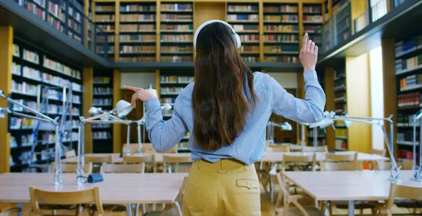 Retrato de una hermosa joven sonriendo feliz en una biblioteca sosteniendo libros después de hacer una búsqueda y después de estudiar. Concepto: educativo, retrato, biblioteca y estudioso . — Foto de Stock