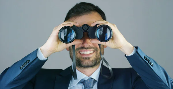 Un hombre de negocios en traje y corbata, utilice los prismáticos para mirar hacia otro lado con el concepto de mirar hacia el futuro, pronosticando el crecimiento económico y financiero y el futuro —  Fotos de Stock