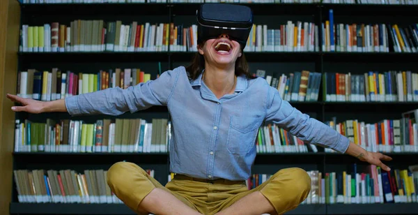 Uma bela jovem em uma biblioteca viaja em um mundo futurista virtual com realidade aumentada. Conceito: educacional, futuro, biblioteca e tecnologia imersiva . — Fotografia de Stock