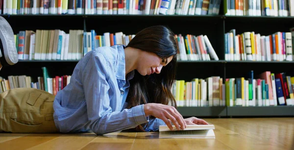 Retrato de uma bela jovem sorrindo feliz em uma biblioteca segurando livros depois de fazer uma pesquisa e depois de estudar. Conceito: educativo, retrato, biblioteca e estudioso . — Fotografia de Stock