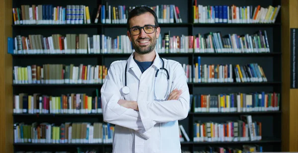 Una joven y hermosa doctora en una biblioteca sonriendo feliz y sosteniendo libros después de hacer una búsqueda y después de estudiar. Concepto: educación, retrato, biblioteca, atención médica y bienestar — Foto de Stock