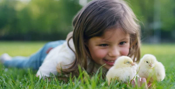 Saat-saat terbaik dari kehidupan, gadis-gadis manis, bermain di taman dengan ayam kecil (kuning), di latar belakang rumput hijau dan pohon, konsepnya: anak-anak, cinta, ekologi, lingkungan, pemuda . — Stok Foto