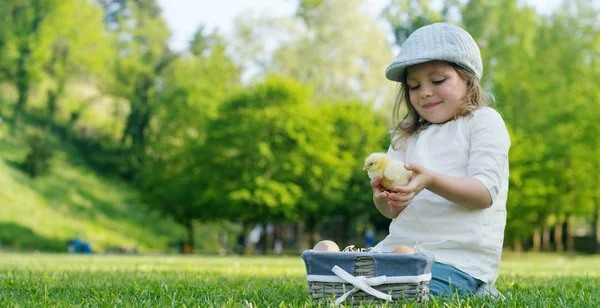 Os melhores momentos da vida, as meninas doces no boné, brinca no parque com pequenas galinhas (amarelo) na cesta, no fundo de grama verde e árvores, o conceito: crianças, amor, ecologia . — Fotografia de Stock