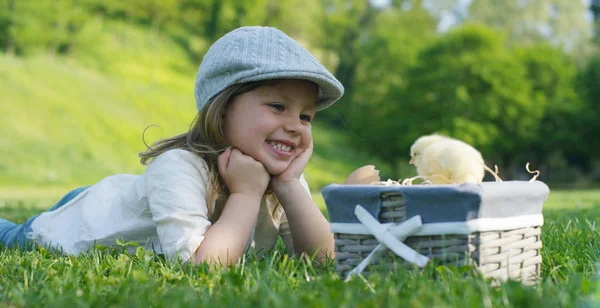 Saat-saat terbaik dari kehidupan, gadis-gadis manis di topi, bermain di taman dengan ayam kecil (kuning) di keranjang, di latar belakang rumput hijau dan pohon, konsepnya: anak-anak, cinta, ekologi . — Stok Foto