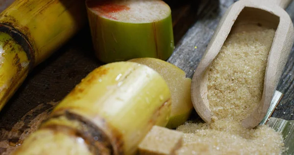 Ett makro skott av en sammansättning av sockerrör, sockerbitar och socker i raw granulerna. Koncept: ett sötningsmedel, natur, energi, juicer och drinkar. — Stockfoto